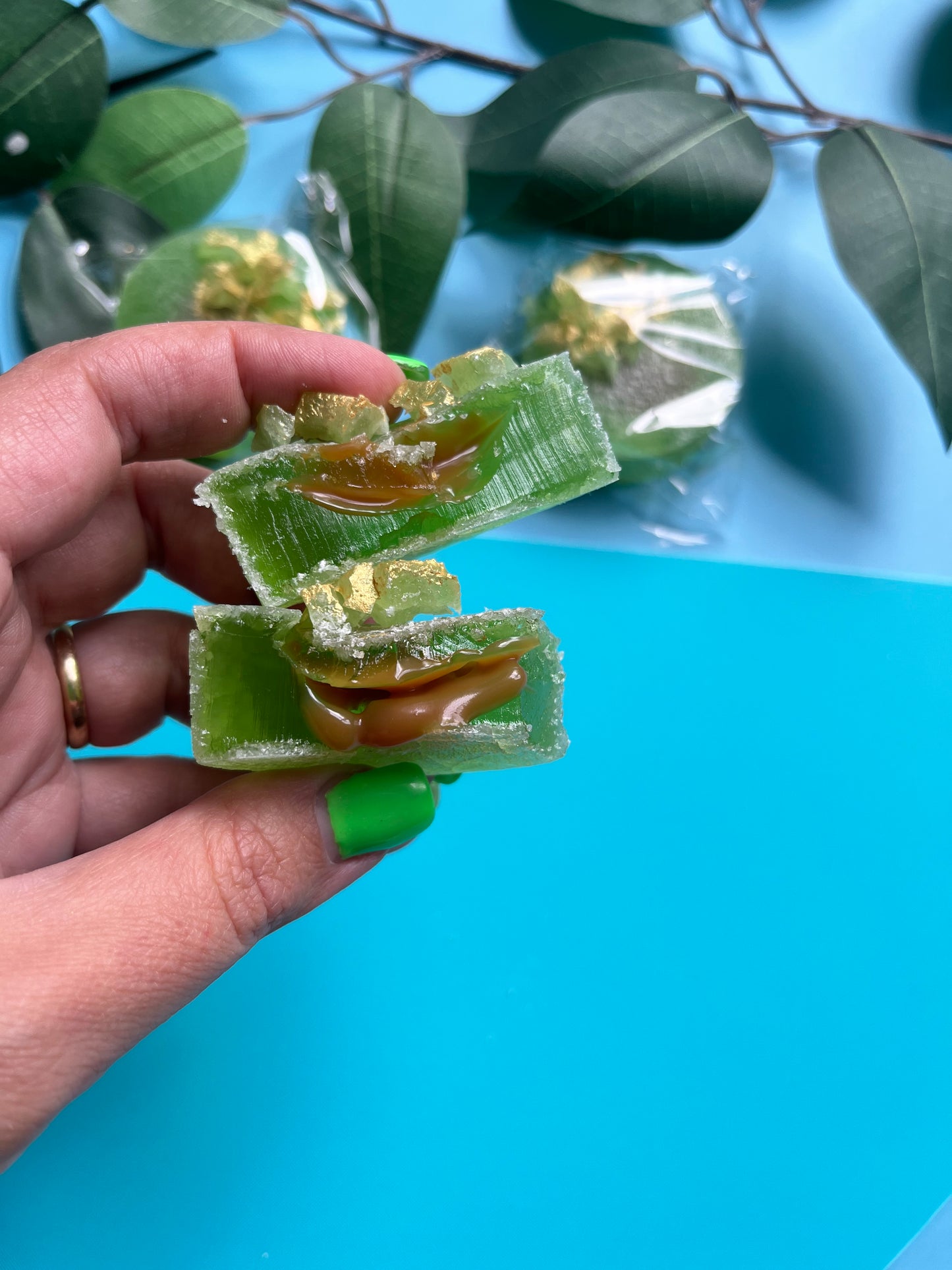 Bite-shot showing sticky caramel oozing from green candy shell, with a luxury vibe