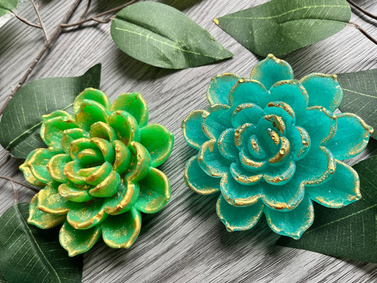 Close-up of edible crystal candy lotus flowers with gold-painted accents on a grey fabric