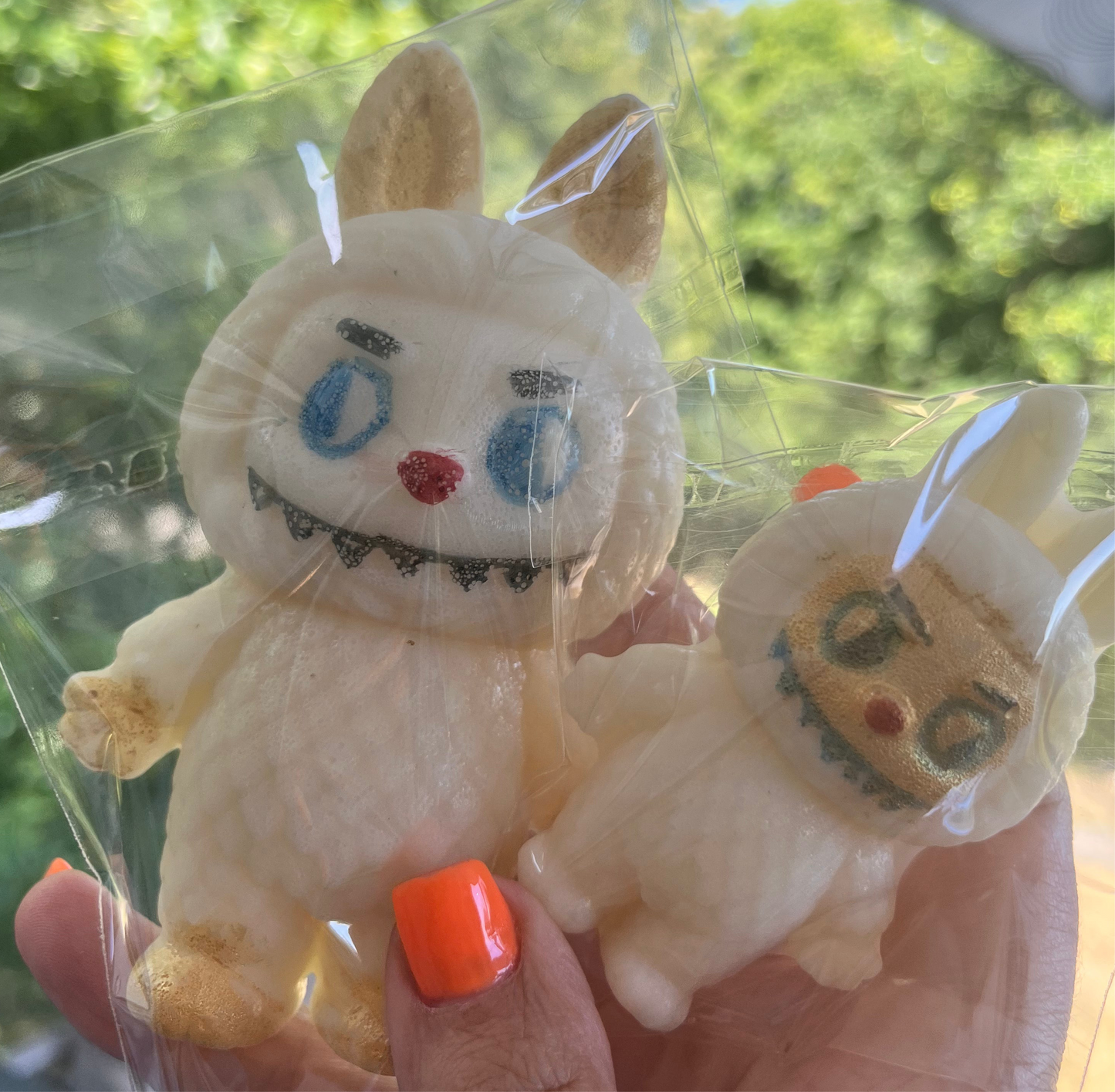 Close-up of hand holding Labubu Crystal Candy in sunlight, showing details of eyes, smile, and texture