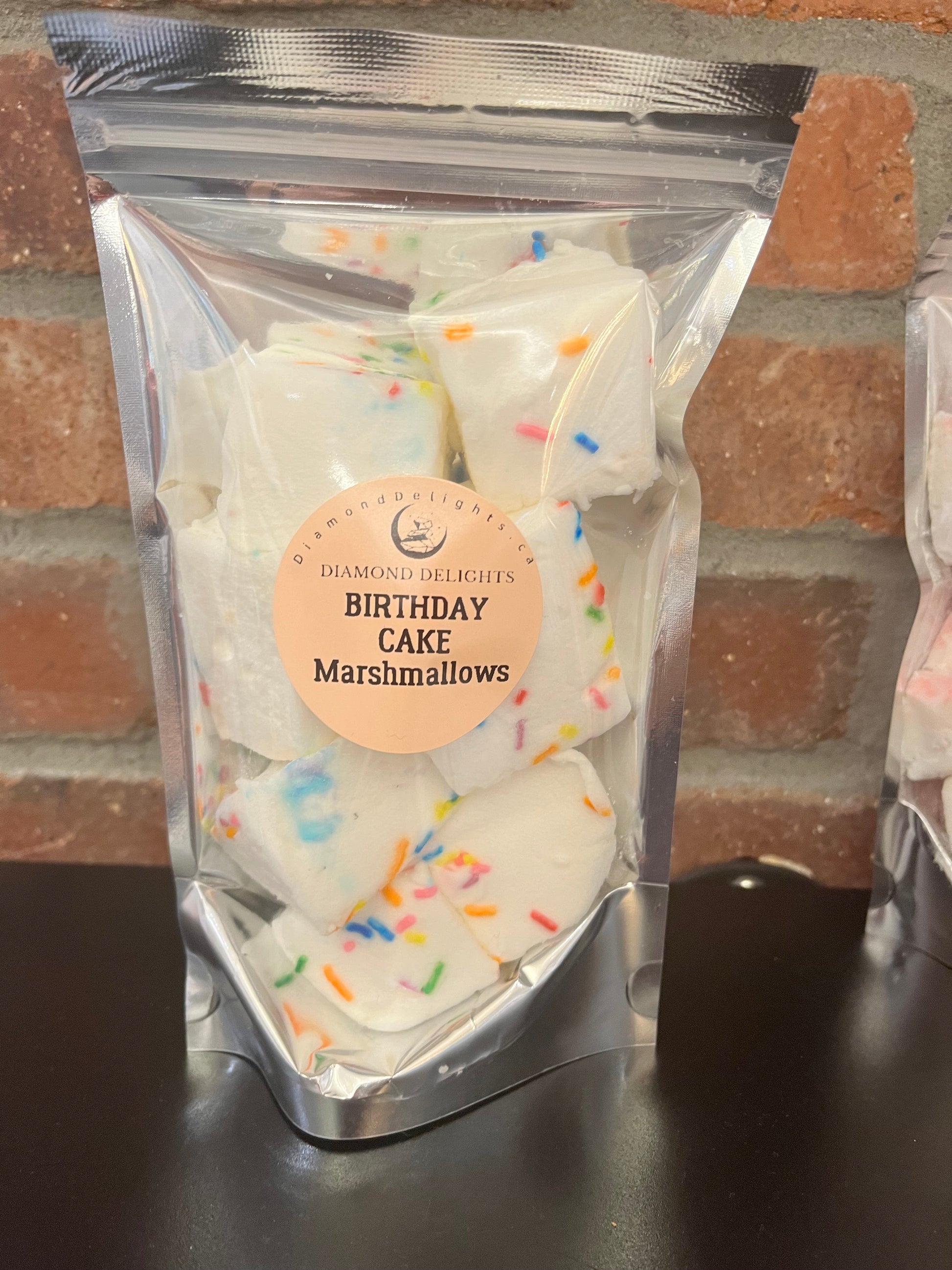 Bag of fluffy birthday cake marshmallows topped with rainbow sprinkles in a clear resealable pouch.