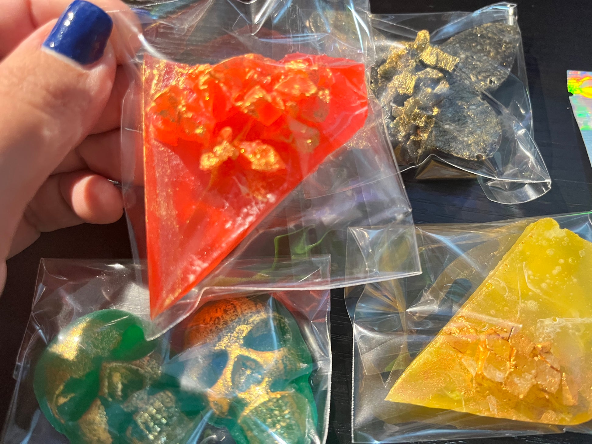 Close-up of vibrant handmade crystal candies in a gift box, including galaxy skulls and a butterfly gem, individually wrapped
