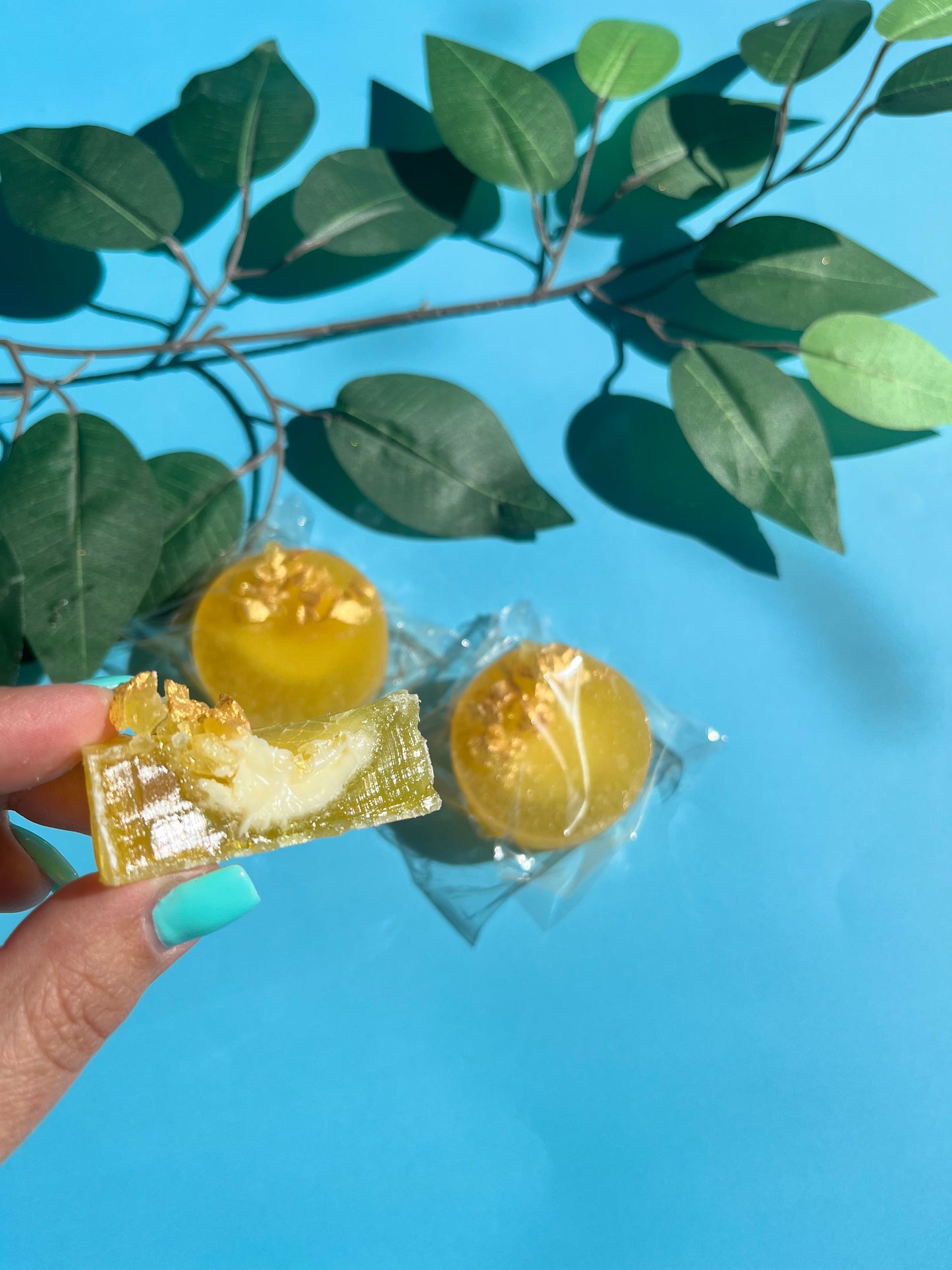 Lemon kohakutou crystal candy with citrus cheesecake filling, topped with crystal shards and gold paint, shown close-up with a bite taken out.