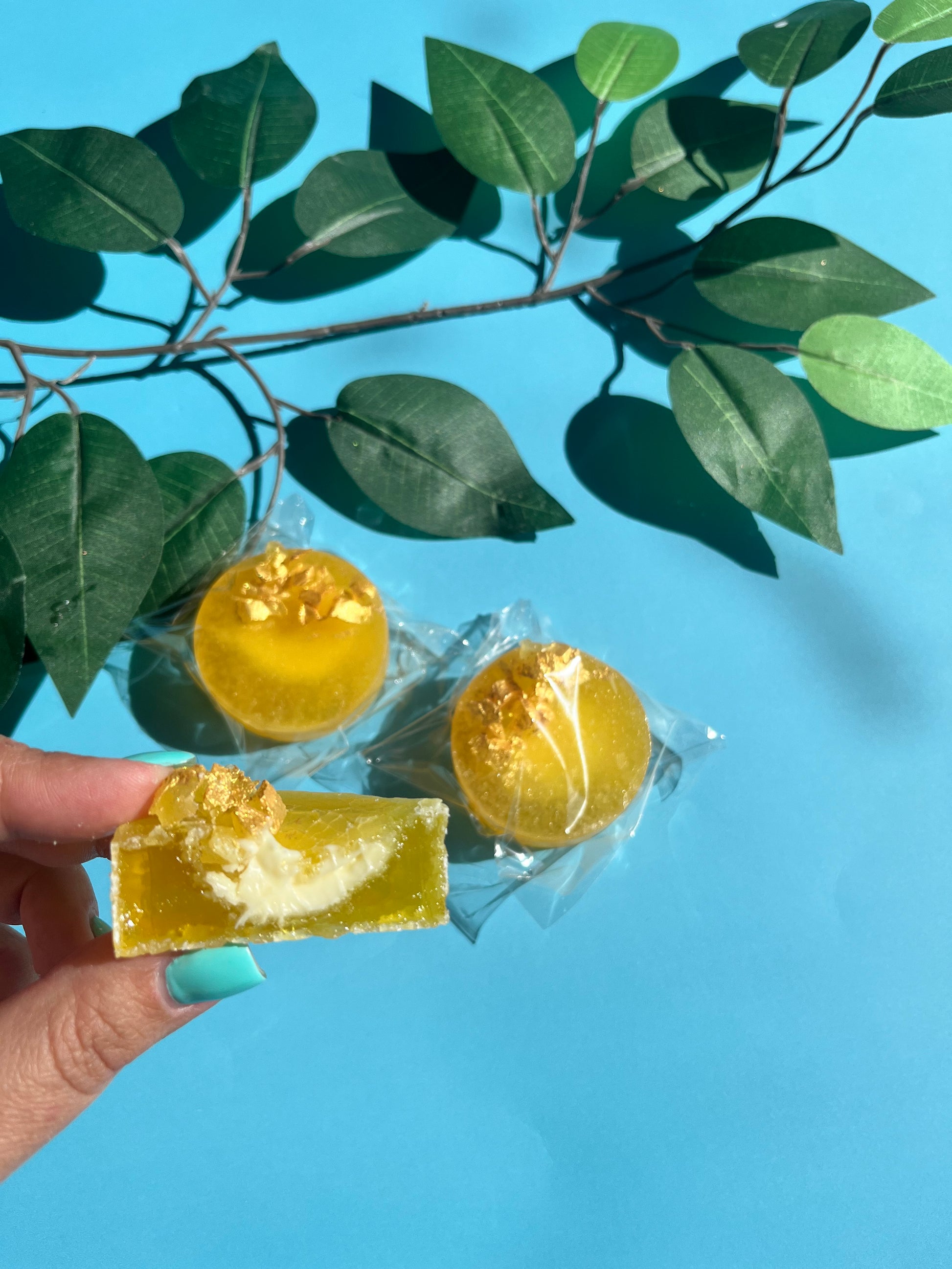 Lemon kohakutou crystal candy with citrus cheesecake filling, topped with crystal shards and gold paint, shown close-up with a bite taken out.