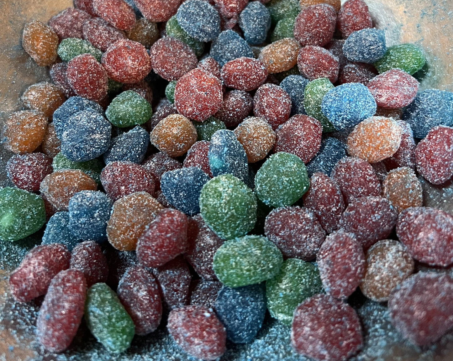 Flavoured Gushers covered in sweet and sour powder, assorted bright colors in a close-up view of the candy.
