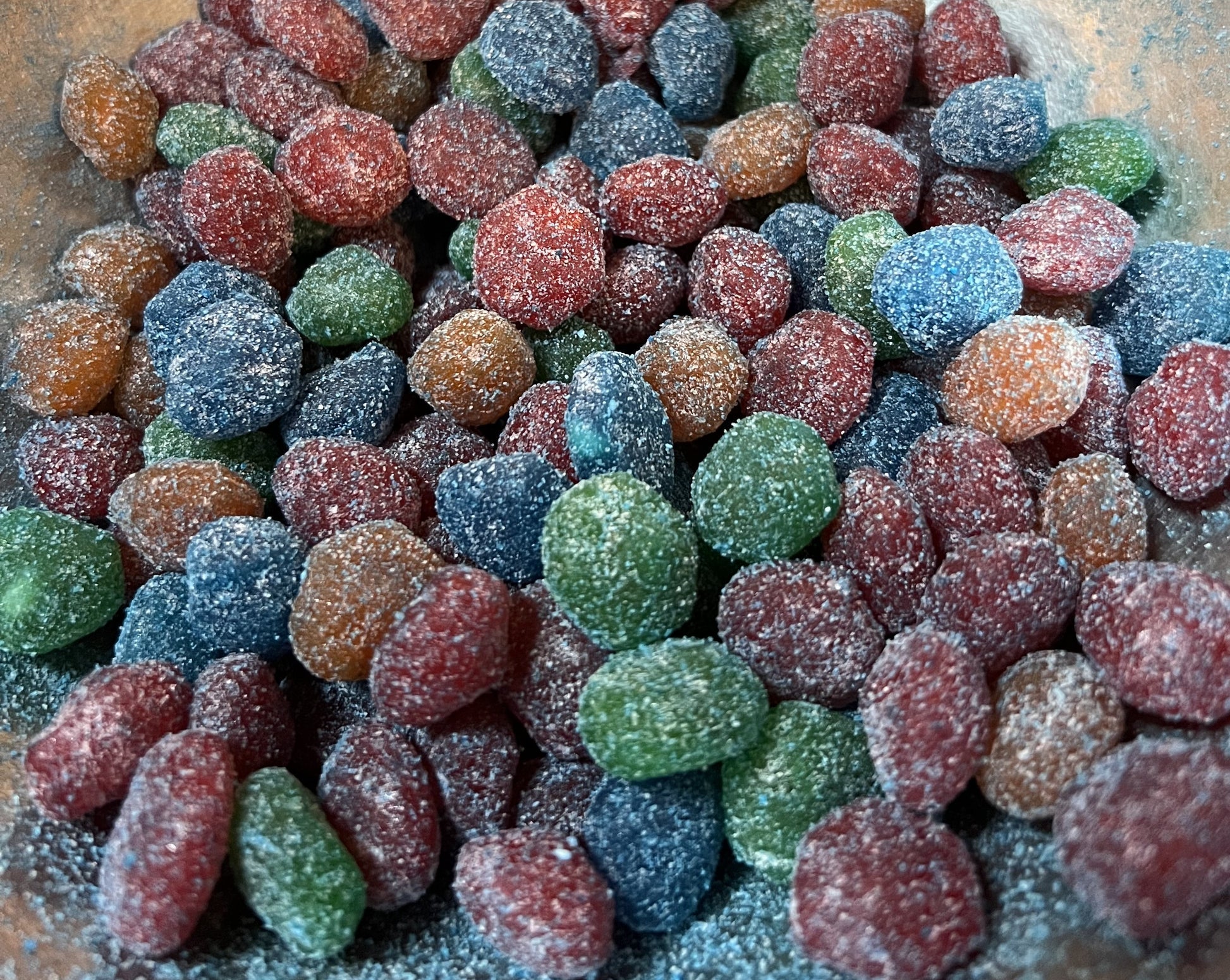 Flavoured Gushers covered in sweet and sour powder, assorted bright colors in a close-up view of the candy.