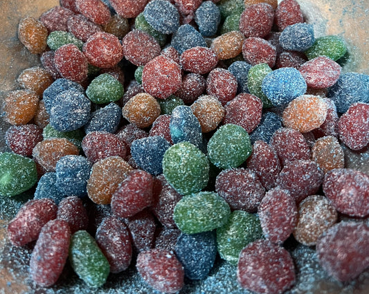 Flavoured Gushers covered in sweet and sour powder, assorted bright colors in a close-up view of the candy.