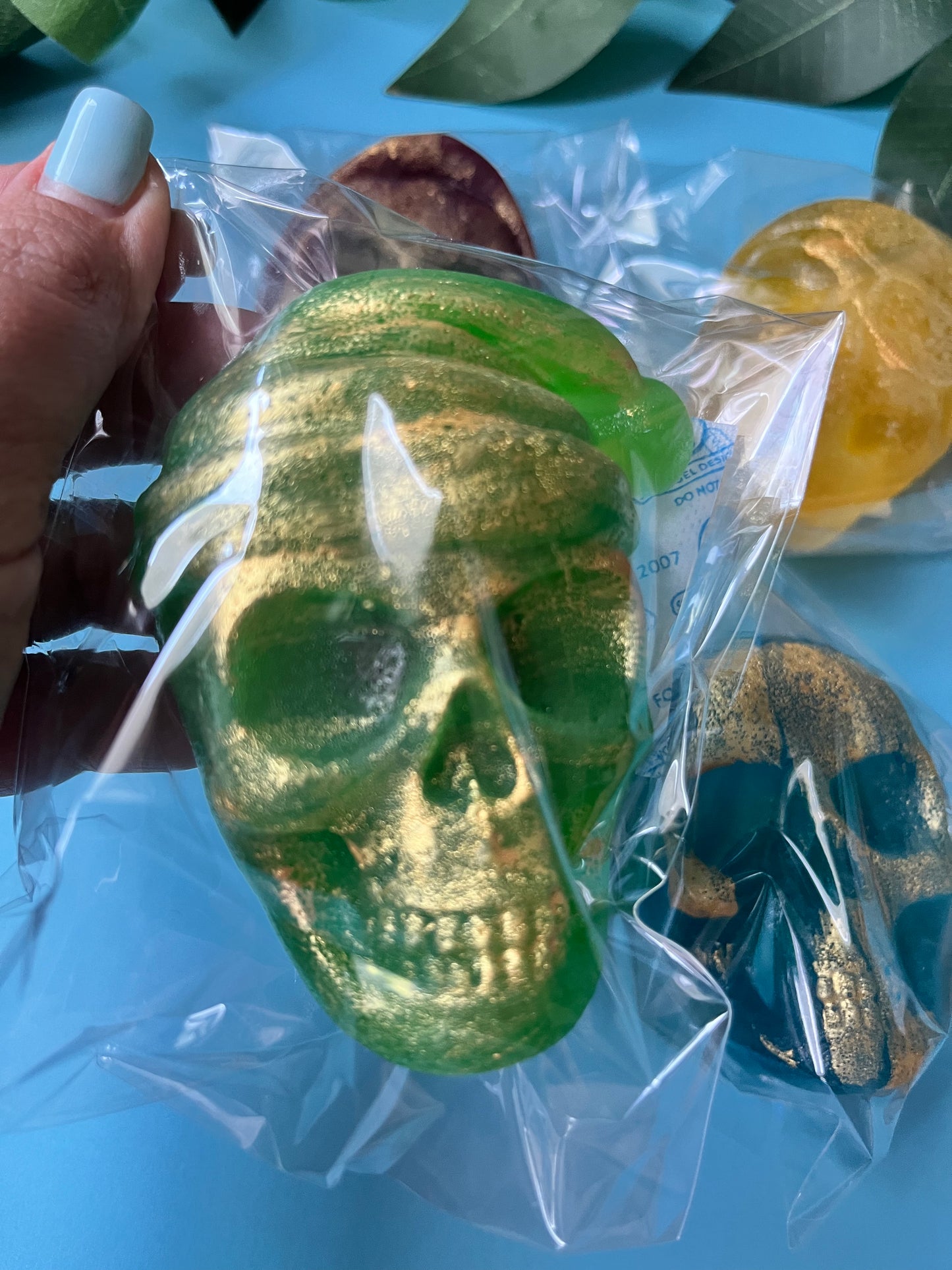 Green skull-shaped object in clear packaging with a blue background