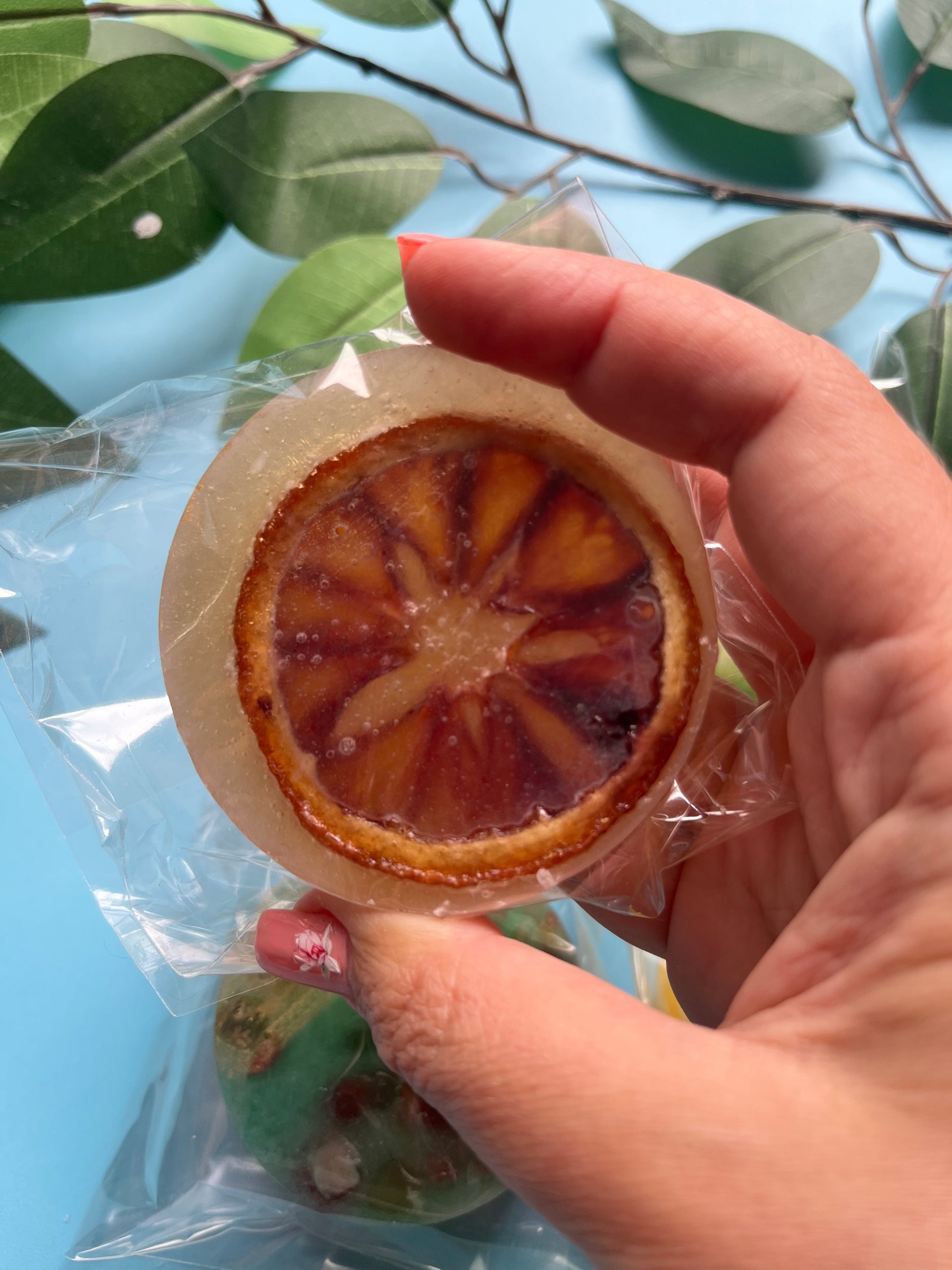 Golden yellow amaretto candy featuring a full dried orange slice, glowing through the transparent crystal shell.