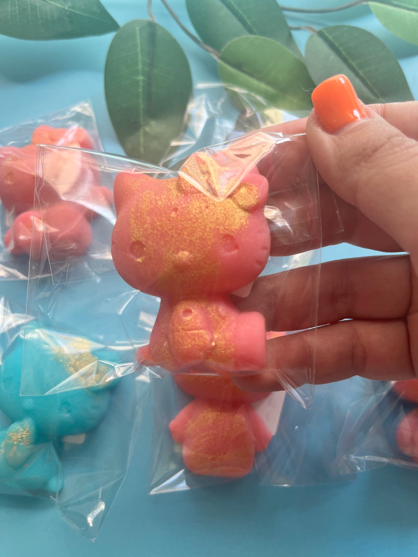 Hand holding a pink Hello Kitty candy with a blue background