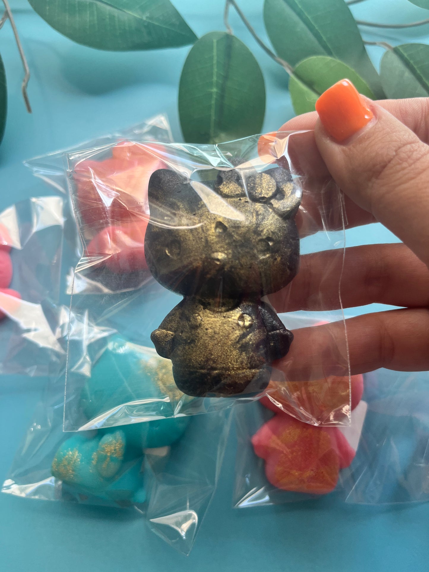 Bronze edible Hello Kitty candy held by a hand with colorful background