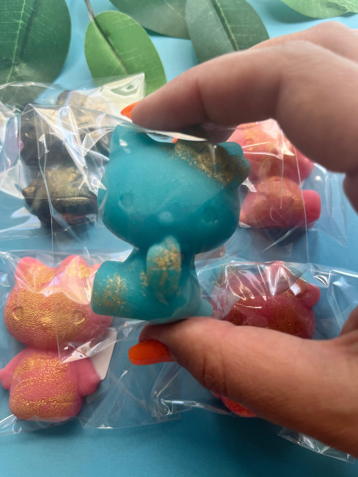 Hand holding a blue and gold Hello Kitty candy with wrapped candies in the background.