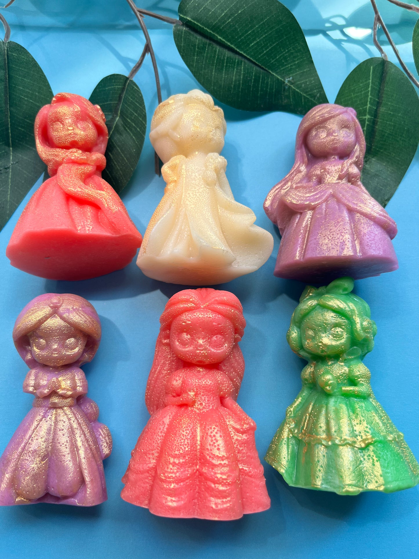 Set of colorful figurines on a blue surface with green leaves.