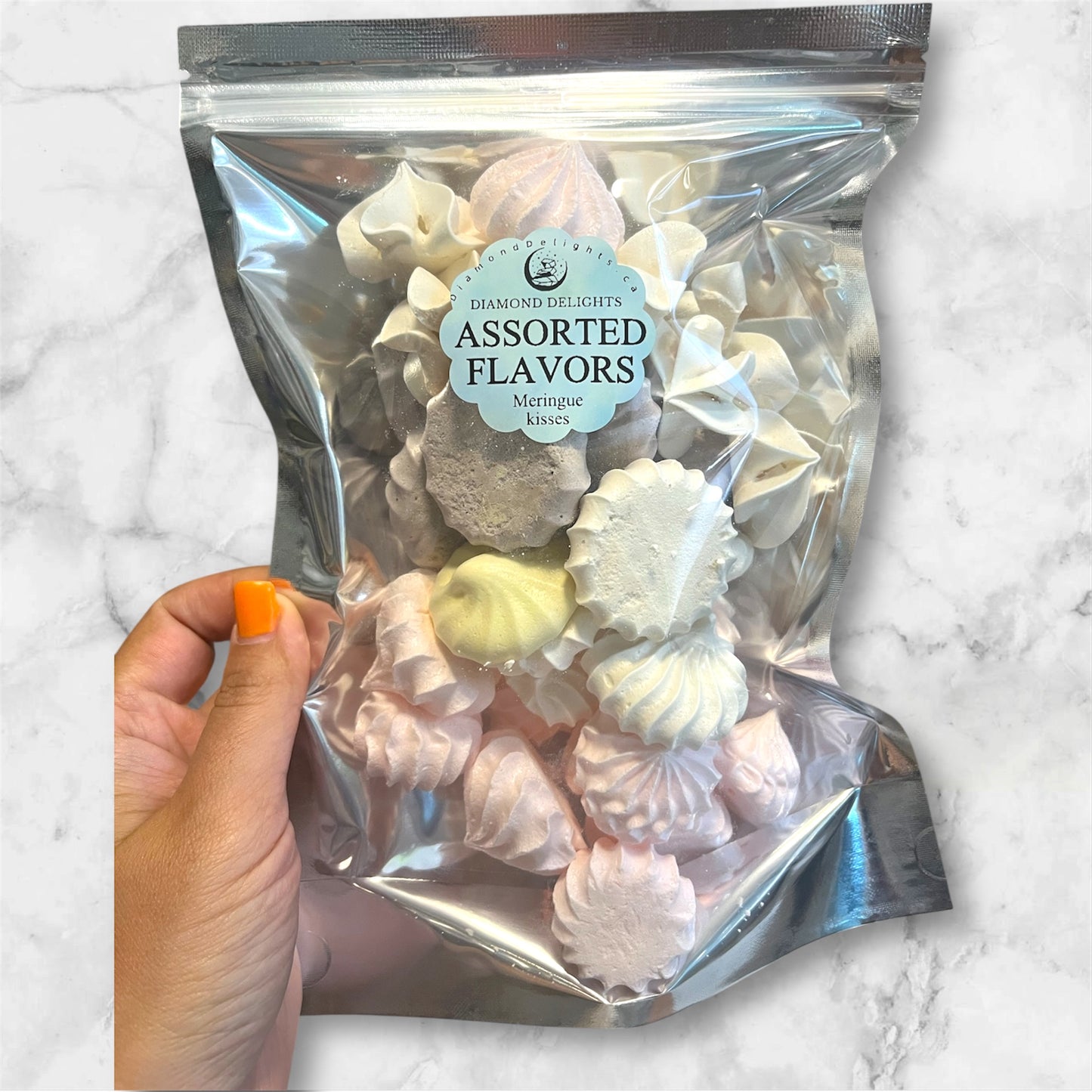 Assorted meringue kisses in a clear resealable bag, handmade in pastel colors like pink, yellow, white, and chocolate, labeled ‘Diamond Delights Assorted Flavors’