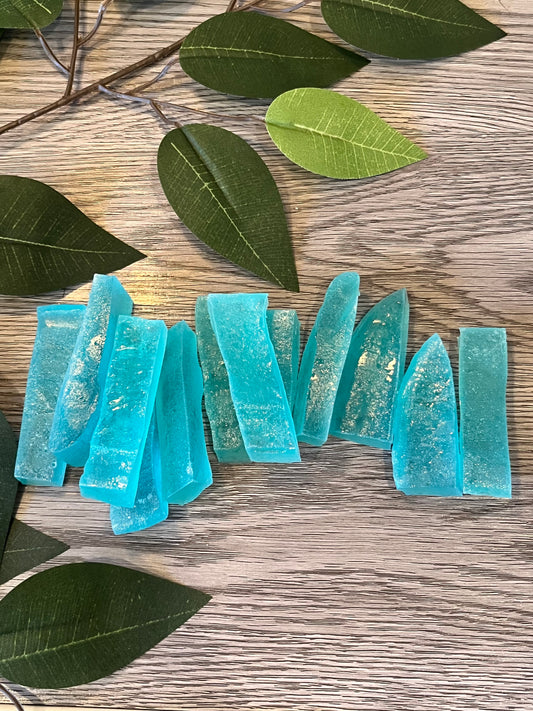 Blue gem-shaped crystal candy in a clear pouch from Diamond Delights, kohakutou style, on wood with green leaves