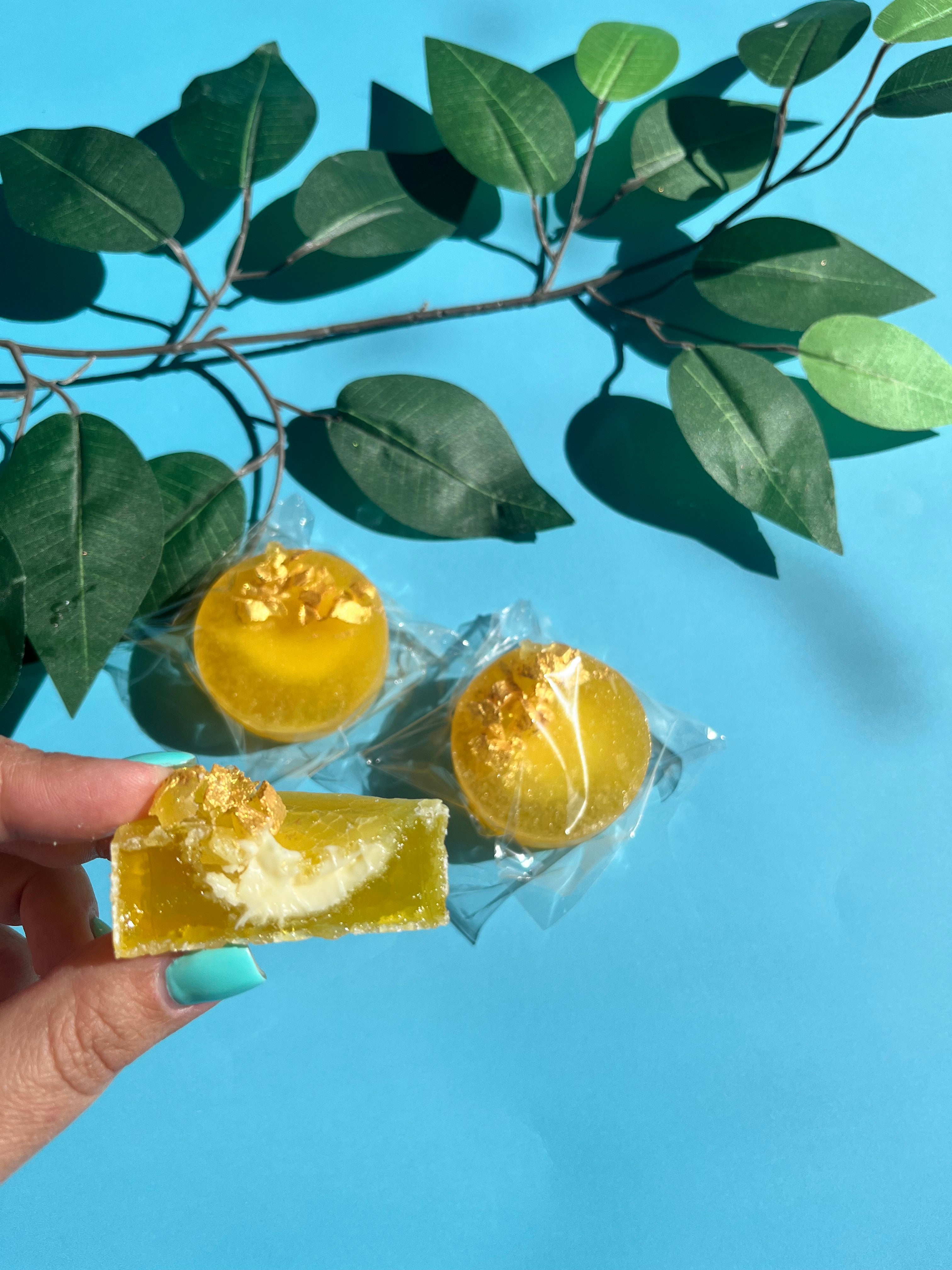 Lemon kohakutou crystal candy with citrus cheesecake filling, topped with crystal shards and gold paint, shown close-up with a bite taken out.