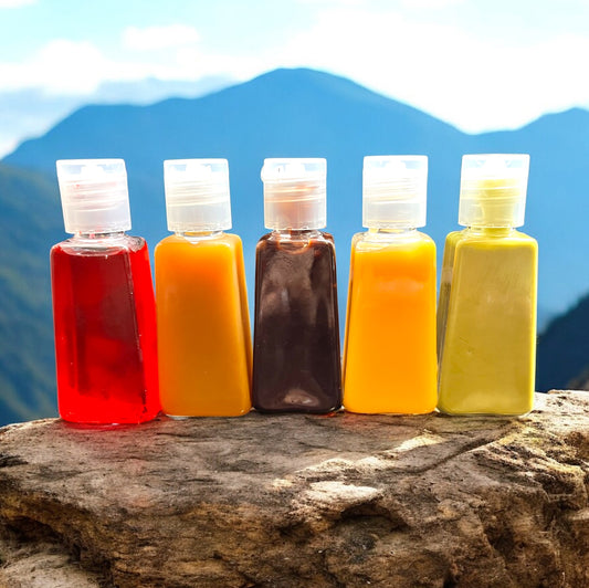 Five small bottles with colorful liquids on a rock with mountains in the background