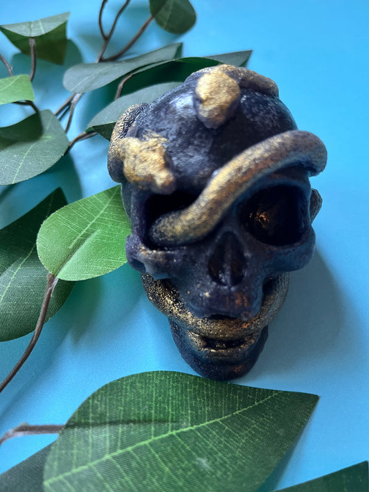 Crystal Candy skull with gold accents on a blue background with green leaves