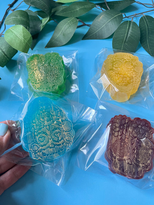 Four colorful crystal candy in clear packaging on a blue surface with green leaves.