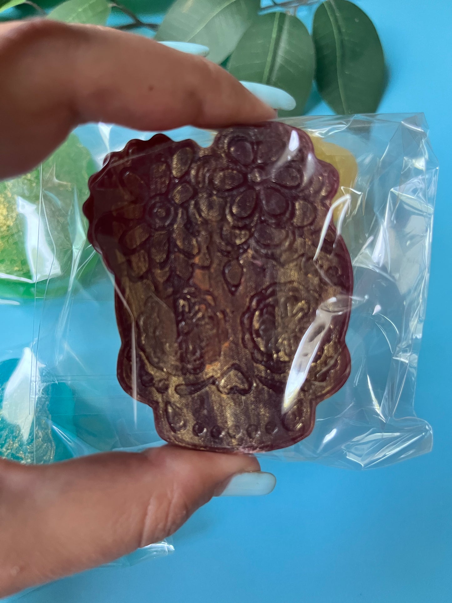 Decorative chocolate bar with intricate design held by a hand against a blue background