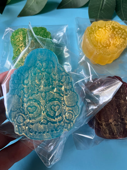 Delicious crystal candy in clear packaging on a blue surface with green leaves.