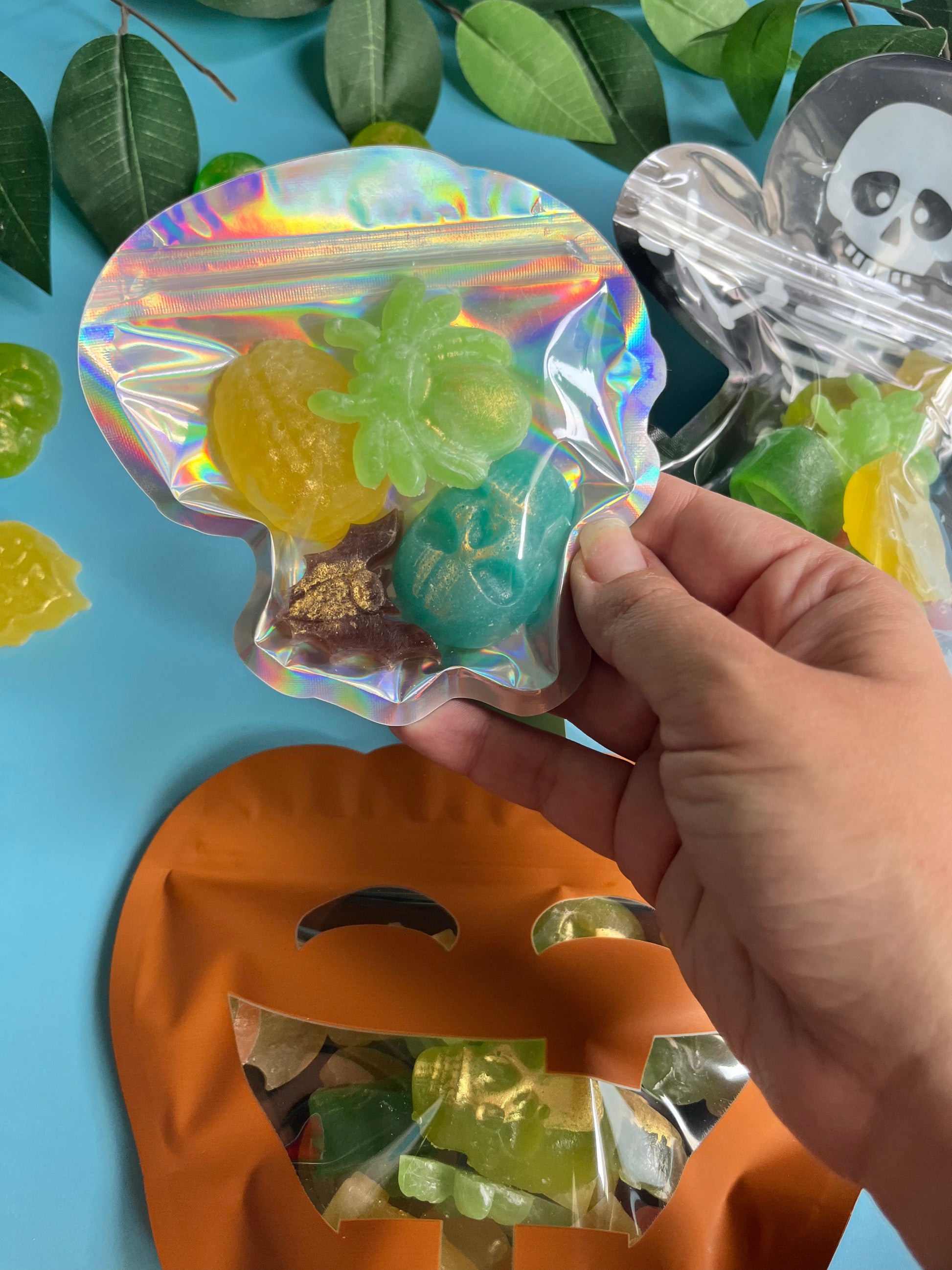 Hand holding a holographic bag with gummy candies against a colorful background