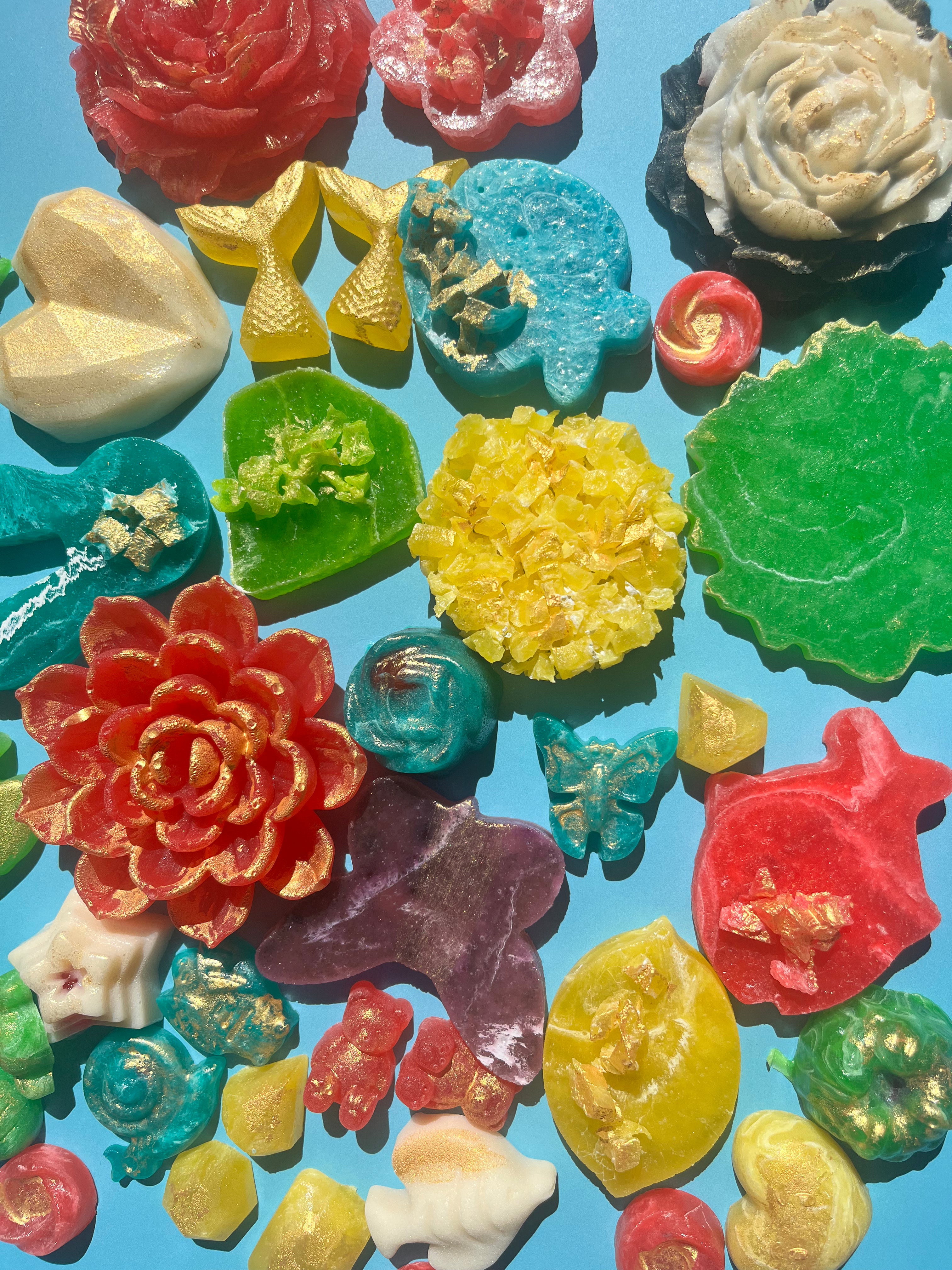 Wide assortment of handmade crystal candies in whimsical shapes and bright colors on blue background